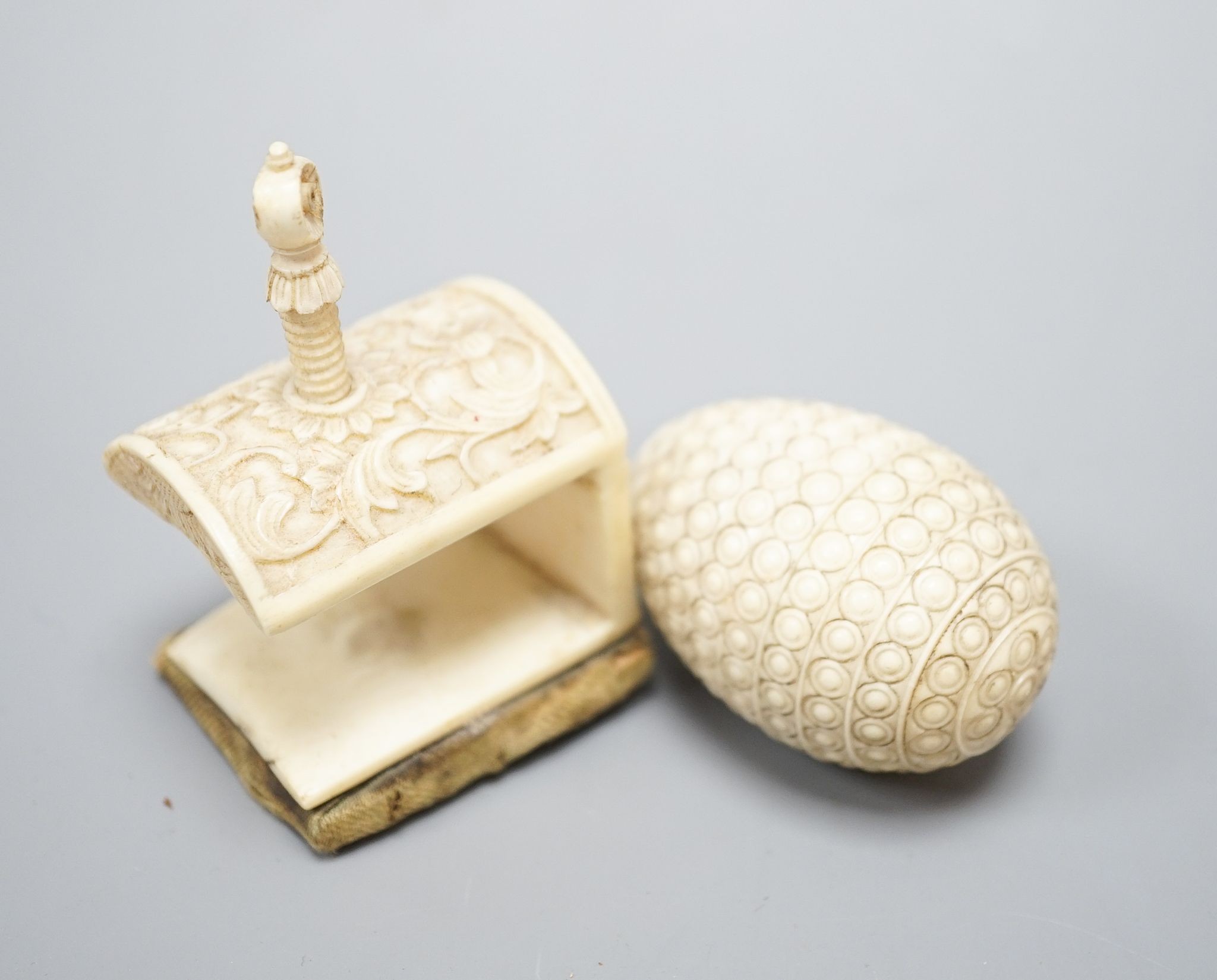 Ivory egg-shaped thread storage case and carved ivory needle-worker's table clamp, clamp, 6 cms high.